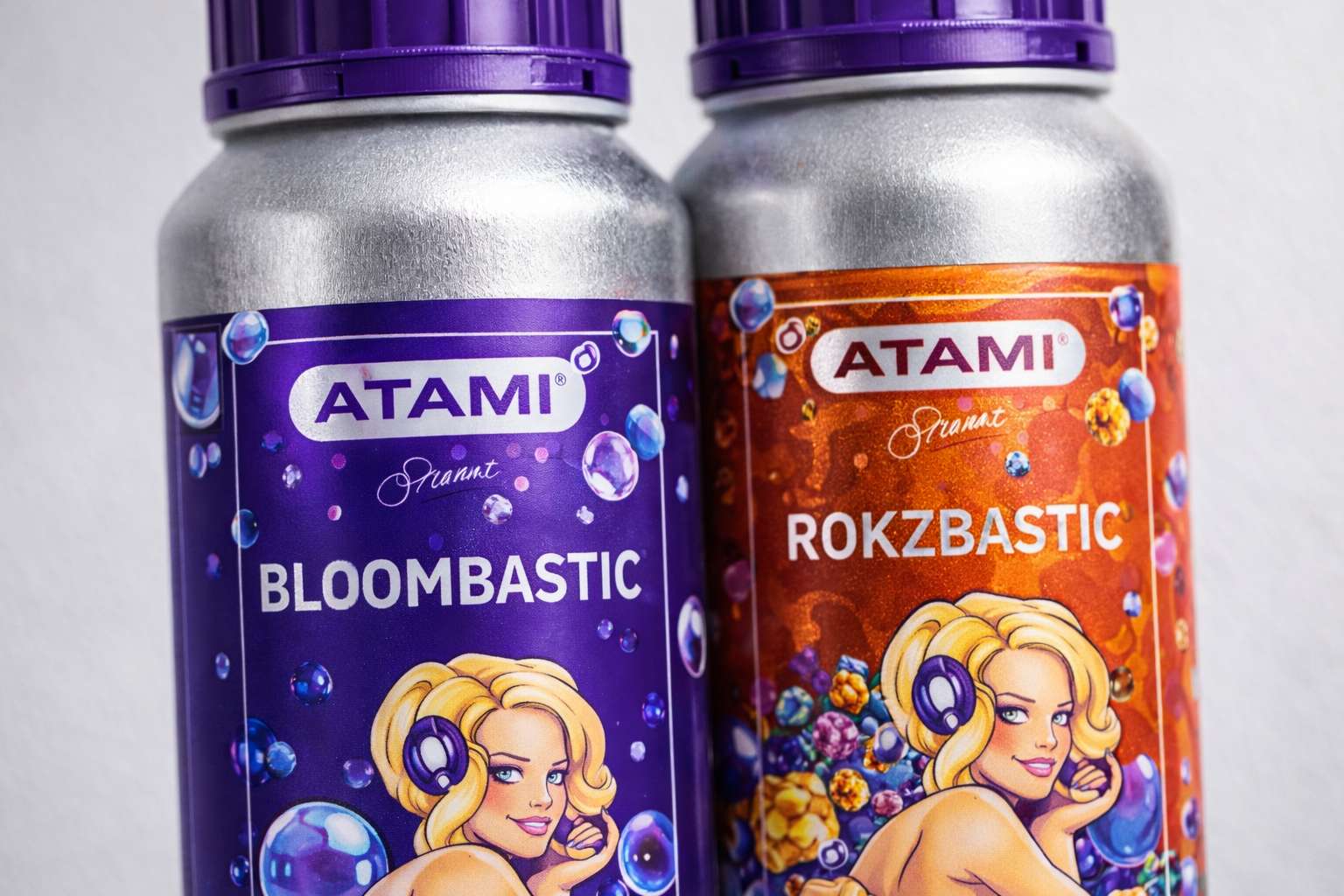 Detalle cercano de las botellas Atami B’Cuzz Bloombastic y Rokzbastic con etiquetas morada y naranja y tapones violeta