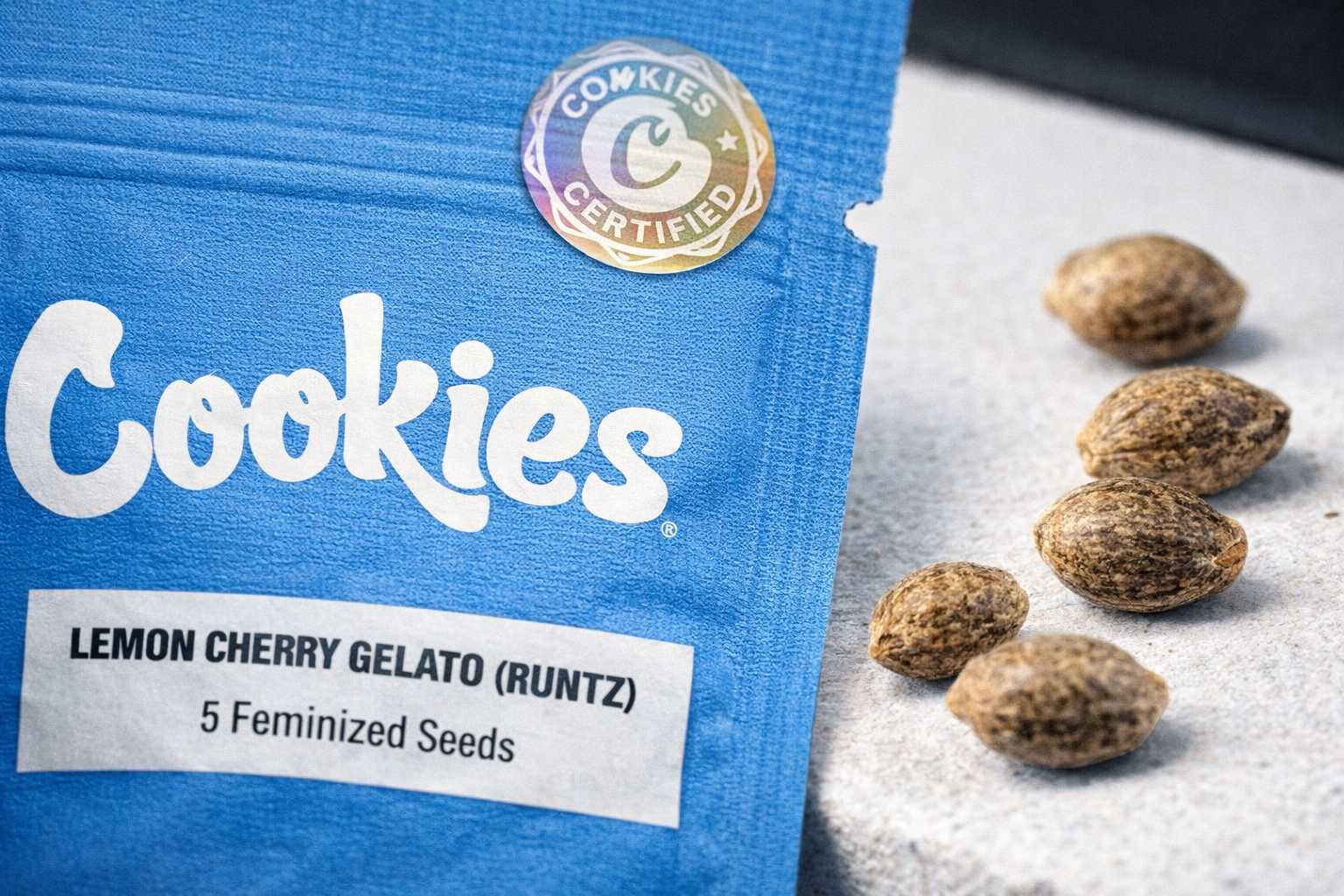 Sello Cookies Certified en bolsa azul de Cookies Seed Bank junto a semillas sobre superficie clara