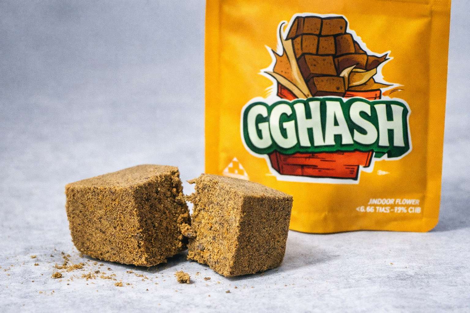 Detalle de bloques de resina frente a una bolsa GG Hash de Gorilla Grillz sobre superficie clara, con migas de producto