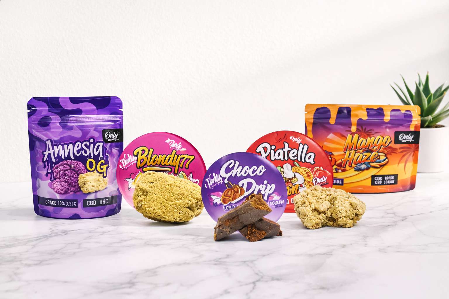 Gama Only CBD con bolsa Amnesia OG y envase Mango Haze, discos Blondy77 y Choco Drip, y piezas de resina sobre superficie clara